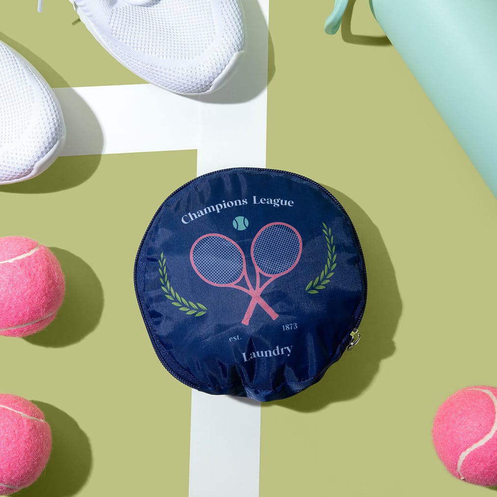 The Tennis Collection laundry bag from Miamica is a cute, navy blue round laundry bag with pink tennis racket motif.